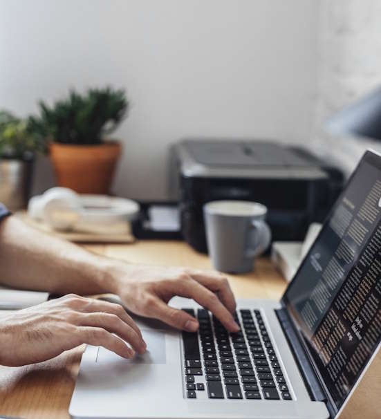 Hands of cropped unrecognisable man typing on his laptop at office.