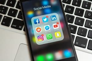 A smartphone showcasing social media app icons, such as Facebook, Twitter, and LinkedIn—key tools in social media marketing for businesses—rests on a laptop keyboard, highlighting the digital landscape's vibrant connectivity.